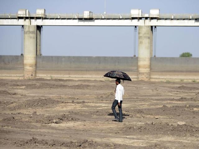 An man holds an umbrella as he walks on the dry reservoir bed next to Gunda Dam by Gunda village in Botad district, 150 km from Ahmedabad. Vast regions of western India have been facing acute water shortages due to drought conditions. (AFP Photo) An man holds an umbrella as he walks on the dry reservoir bed next to Gunda Dam by Gunda village in Botad district, 150 km from Ahmedabad. Vast regions of western India have been facing acute water shortages due to drought conditions. (AFP Photo)