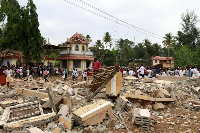 People walk past debris after a fire broke out at a temple in Kollam in Kerala. (REUTERS) People walk past debris after a fire broke out at a temple in Kollam in Kerala. (REUTERS)