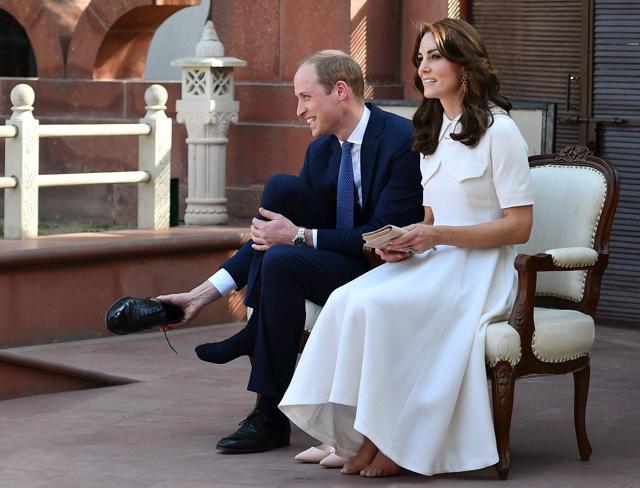 Britain's Prince William and his wife, Kate Middleton, the Duchess of Cambridge, put off their shoes before paying homage to Mahatma Gandhi during a visit to ''Gandhi Smriti'' in New Delhi on Monday. (PTI)