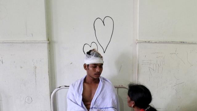 A relative sits next to the bed of a victim, who was injured in a fire at a temple at a hospital in Kollam. (Reuters Photo)