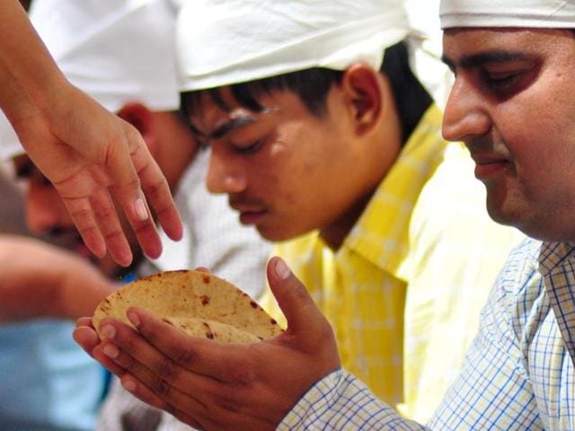 A devotee taking ‘prasada’ (chapati) at the langar hall of a gurdwara. (HT Photo)