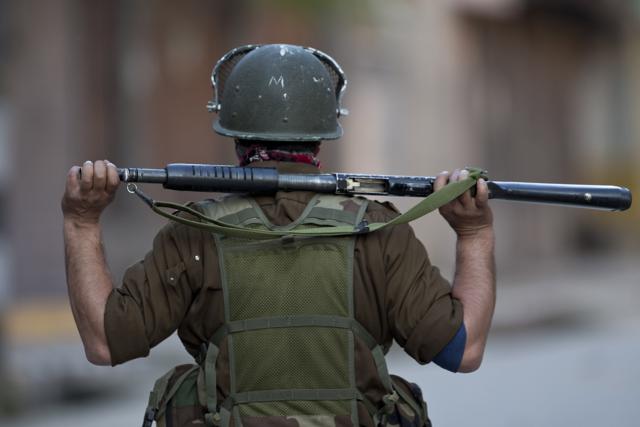 A policeman looks from distance during their clashes with Kashmiri Muslim protesters  in Srinagar. While three people were killed in Tuesday’s firing, another person died on Wednesday.  (AP) 