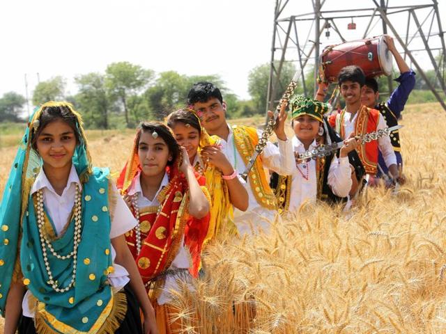 School students dressed in colourful attires while celebrating Baisakhi in the fields in Singhpura village of Rohtak. (Manoj Dhaka/HT)