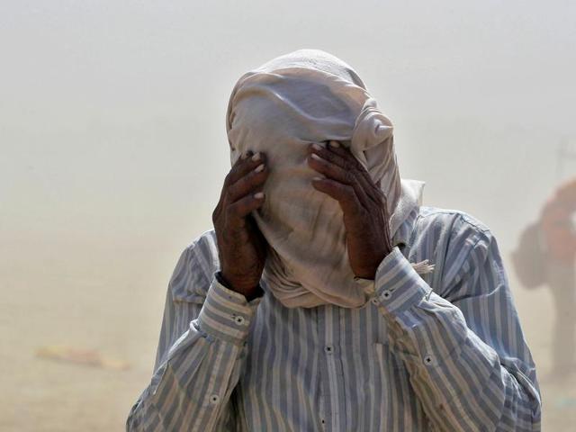 A man covers his face as he walks through a dust storm on the banks of the Ganga river in Allahabad. (REUTERS)