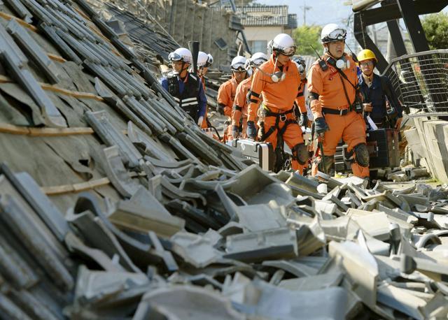 Firefighters walk among collapsed houses caused by an earthquake in Mashiki town, Kumamoto prefecture, southern Japan. (Reuters)