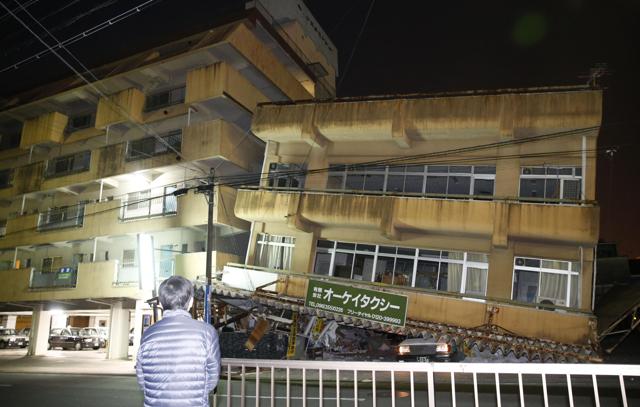 A man stands in front of a building collapsed by an earthquake in Kumamoto. (AP)