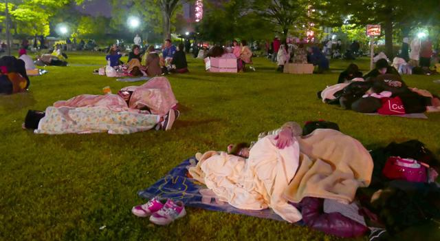 People rest on grass in fear of aftershock at an evacuation site in Kumamoto. (AP)