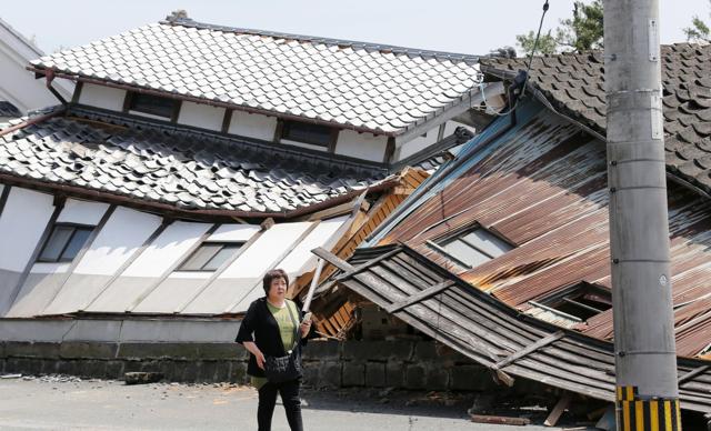 A woman walks past houses destroyed by Thursday's earthquake in Mashiki, Kumamoto prefecture, southern Japan, Friday, April 15, 2016. (AP)