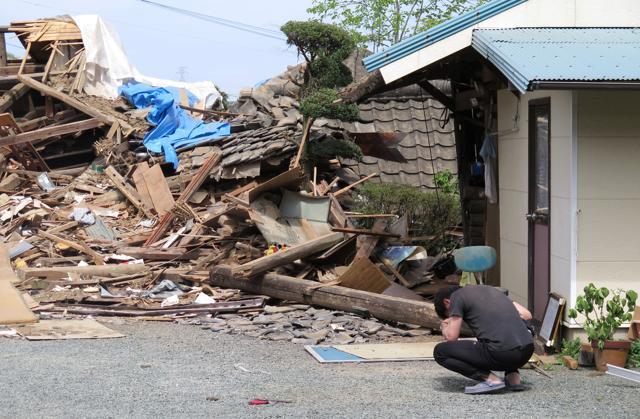 A man hunks down in front of a collapsed residence where his mother is being trapped after an earthquake in Mashiki, Kumamoto prefecture. (AP) A man hunks down in front of a collapsed residence where his mother is being trapped after an earthquake in Mashiki, Kumamoto prefecture. (AP)