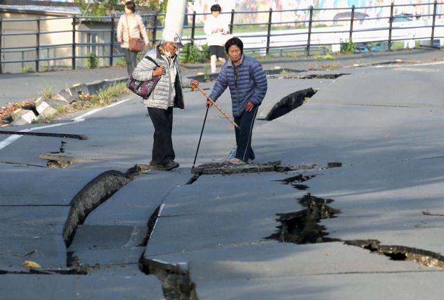 Local residents look at cracks caused by an earthquake on a road in Mashiki town. (REUTERS)