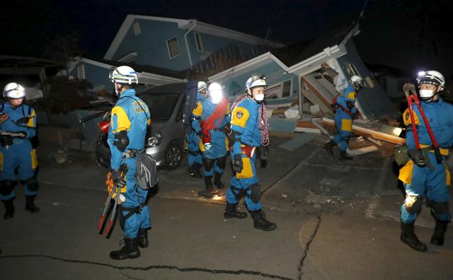 Police officers check a collapsed house after an earthquake in Mashiki town. (REUTERS)