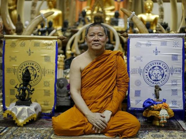 Buddhist monk Phra Prommangkalachan poses for a portrait next to holy cloths with Leicester City's logo. (Reuters Photo)