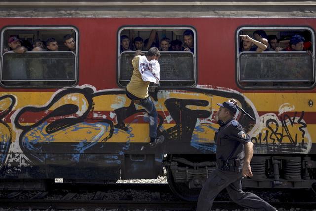 A policeman tries to stop a migrant from boarding a train through a window at Gevgelija train station in Macedonia, close to the border with Greece. (REUTERS) A policeman tries to stop a migrant from boarding a train through a window at Gevgelija train station in Macedonia, close to the border with Greece. (REUTERS)