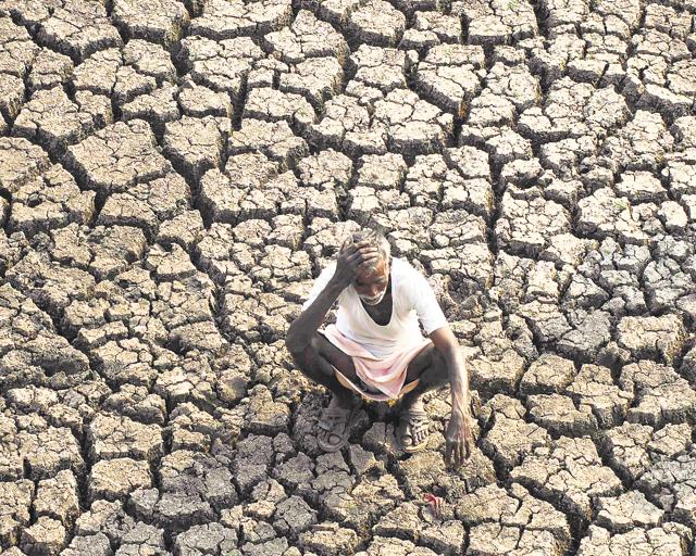 A farmer sits on a dried-up bed of a water body on the outskirts of Hyderabad. (File photo/AP)