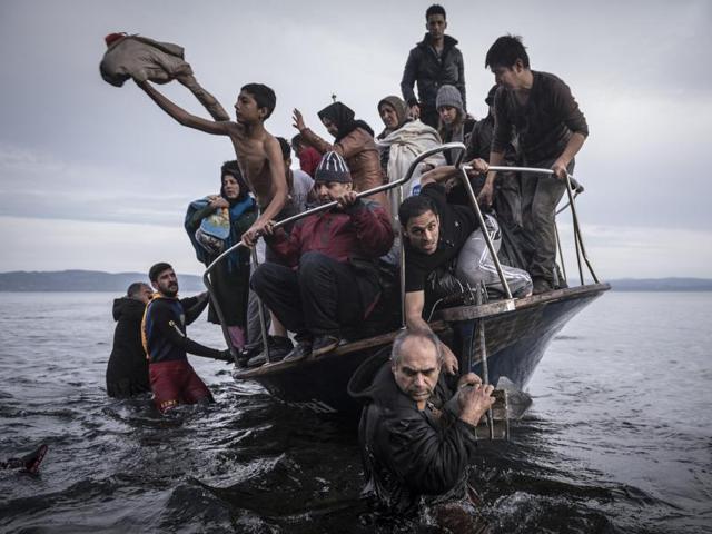 A small boat filled with migrants come ashore after making the crossing from Turkey, near the village of Skala, on Lesbos island in Greece, Nov. 16, 2015. Mauricio Lima, Sergey Ponomarev, Tyler Hicks and Daniel Etter of The New York Times won the 2016 Pulitzer Prize for what the Pulitzer committee said were photographs that captured the resolve of refugees, the perils of their journeys and the struggle of host countries to take them in. (Sergey Ponomarev/NYT via AP)