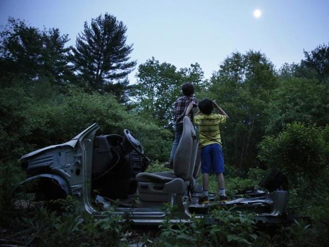 In this May 2015 photo, Strider and Gallagher Wolf play on an abandoned Ford at twilight. This was one of the images by Jessica Rinaldi, of The Boston Globe, that won the Pulitzer Prize for feature photography for photos of a boy who strives to find his footing after being abused. (Jessica Rinaldi/The boston Globe via AP )