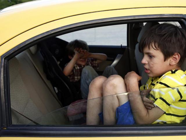 In this May 2015 photo, Strider and Gallagher Wolf sit unattended in the back of the car in Maine. This was one of the images by Jessica Rinaldi, of The Boston Globe, that won the Pulitzer Prize for feature photography for photos of a boy who strives to find his footing after being abused. (Jessica Rinaldi/The boston Globe via AP )