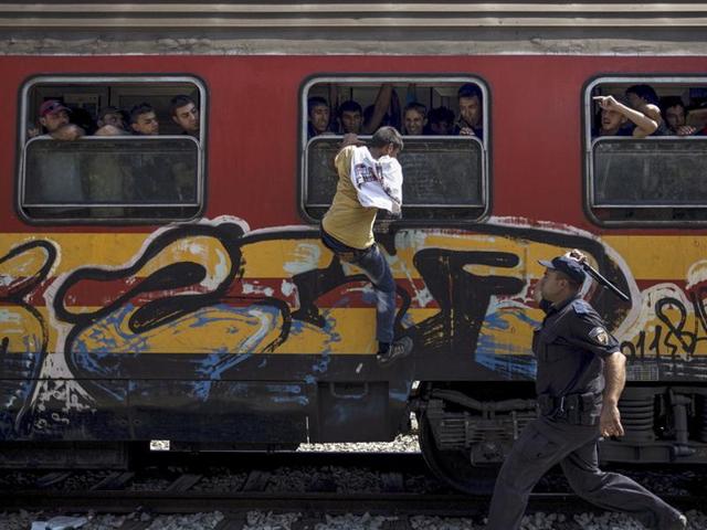 A policeman tries to stop a migrant from boarding a train through a window at Gevgelija train station in Macedonia, close to the border with Greece, August 15, 2015. Reuters and The New York Times shared the Pulitzer Prize for breaking news photography for images of the migrant crisis in Europe and the Middle East. (Stoyan Nenov/REUTERS)