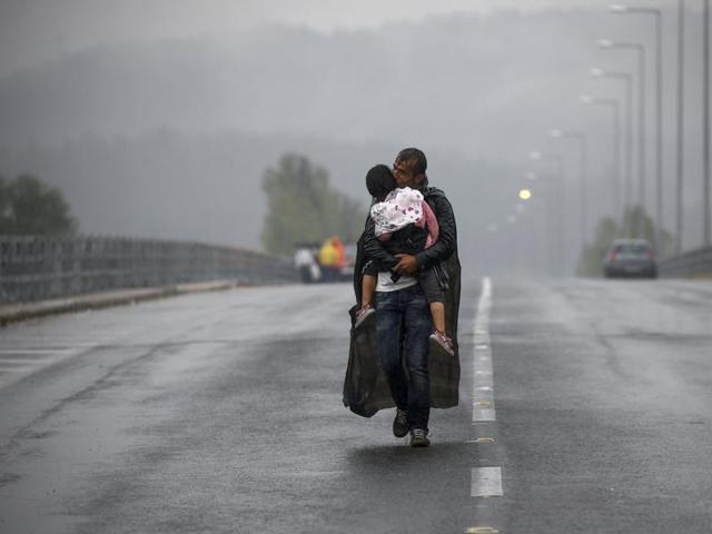 Syrian refugee kisses his daughter as he walks through a rainstorm towards Greece's border with Macedonia, near the Greek village of Idomeni, September 10, 2015. Reuters and The New York Times shared the Pulitzer Prize for breaking news photography for images of the migrant crisis in Europe and the Middle East. (Yannis Behrakis/REUTERS)