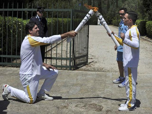 Olympic flame first torch bearer, Greek gymnast Eleftherios Petrounias (R) passes the torch to second bearer, former volleyball player Giovane Gavio from Brazil. (REUTERS Photo)