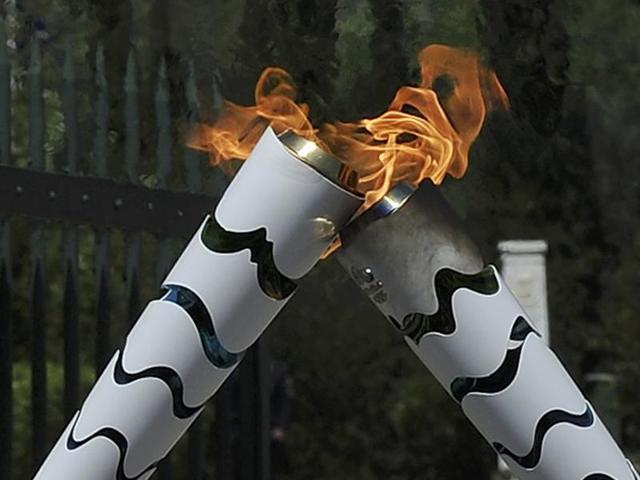 Olympic flame first torch bearer, Greek gymnast Eleftherios Petrounias (R) passes the torch to second bearer, former volleyball player Giovane Gavio from Brazil. (REUTERS Photo)