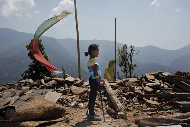 Khendo Tamang, 8, stands near the debris of the collapsed home she was trapped in after the April 25, 2015 earthquake in Banskharka, Nepal. Khendo was in a packed house with her grandmother, sister and other villagers . When the quake struck, the house collapsed, killing her grandmother and her sister and leaving Khendo with severe leg injuries. (AP)