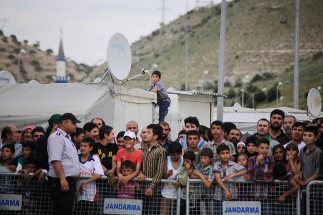 Refugees try to catch a glimpse of the German Chancellor visiting the refugee camp on the Turkish-Syrian border. The proposed deportation plan has come under fire because of the moral and legal implications of it. (AFP Photo) Refugees try to catch a glimpse of the German Chancellor visiting the refugee camp on the Turkish-Syrian border. The proposed deportation plan has come under fire because of the moral and legal implications of it. (AFP Photo)