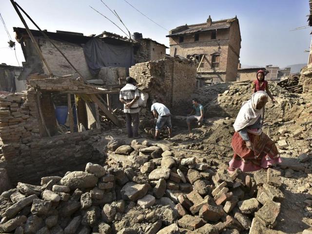 Villagers move through the houses damaged by last year’s earthquake.  (Raj K Raj/Hindustan Times) 