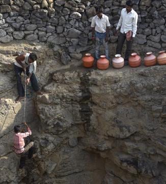 As wells run dry, procuring water has become a task fraught with danger. At a well in Tanda village in Latur, young boys risk their lives, precariously climbing down a 40 feet well to scoop out the remaining water. (Satish Bate/Hindustan Times)