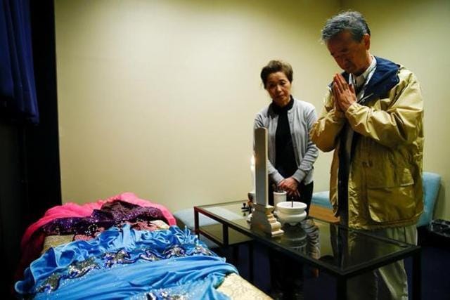 Customer Hirokazu Hosaka (right) prays to his mother as he stands at her coffin with his wife Minako Hosaka at the "corpse hotel" at Kawasaki in Japan. (Reuters)