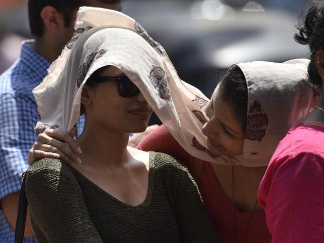 Two women share a scarf to protect themselves from the scorching heat while they wait  for an auto-rickshaw at Bandra station. (Arijit Sen/HT Photo) 