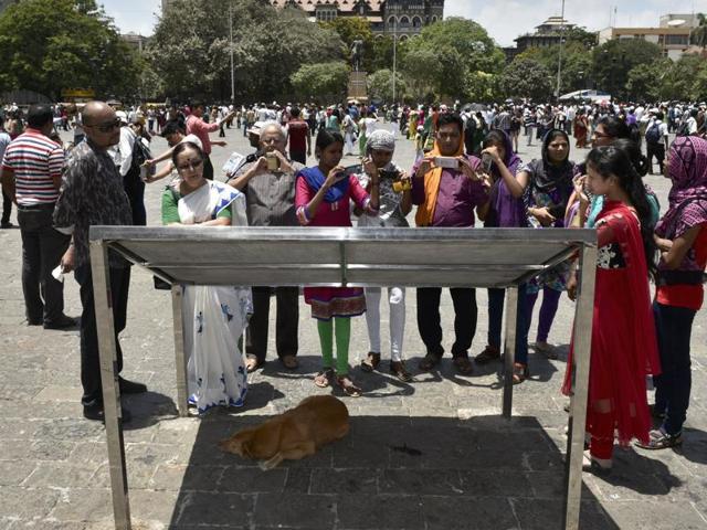 A stray dog rests under the shadow of the tourist information board on a hot and humid afternoon at the Gateway of India in Mumbai. (Arijit Sen/HT Photo) 