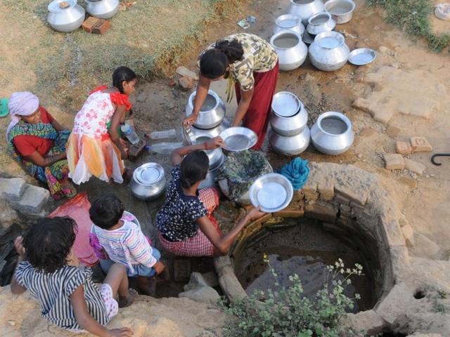 Women collect drinking water from a well near Gadi Hotwar Village as the  residents of this area face a water crisis.   (Parwaz Khan/HT Photo) 