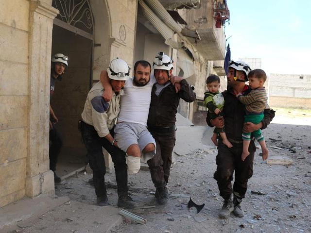 Syrian civil defence volunteers evacuate a man and children from a residential building following a reported air strike on the rebel-held eastern neighbourhood of Bab al-Nayrab in Syria's second city Aleppo.(AFP)