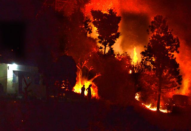 People are seen outside their home as a forest fire rages in Buakhal in Pauri. (Arvind Moudgil / Hindustan Times) People are seen outside their home as a forest fire rages in Buakhal in Pauri. (Arvind Moudgil / Hindustan Times)
