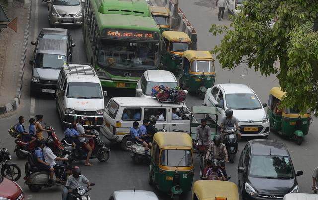 Commuters have their path crossed by a school van and parents on scooters as they drive the wrong way across a road to drop children at a nearby school creating a traffic jam. (AFP)