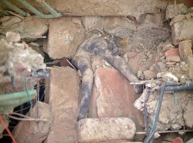 The body of a woman lies trapped between collapsed slabs of concrete as rescuers search for bodies trapped in rubble on May 2, 2016 at the scene of a collapsed residential building in the low-income suburb of Huruma in Nairobi. (AFP) The body of a woman lies trapped between collapsed slabs of concrete as rescuers search for bodies trapped in rubble on May 2, 2016 at the scene of a collapsed residential building in the low-income suburb of Huruma in Nairobi. (AFP)