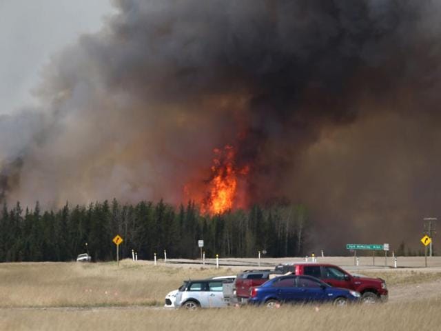 A convoy of evacuees drives south as flames and smoke rises along the highway near near Fort McMurray, (AFP) A convoy of evacuees drives south as flames and smoke rises along the highway near near Fort McMurray, (AFP)