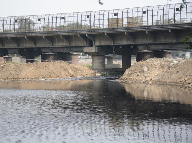 Environmentalists say only a small stream is allowed to flow below the river Hindon Bridge. DMRC has dumped tonnes of soil on the river banks. This is leading to pollution, damage of ecology and will pose problems during the approaching monsoon season. (Sakib Ali/HT Photo) Environmentalists say only a small stream is allowed to flow below the river Hindon Bridge. DMRC has dumped tonnes of soil on the river banks. This is leading to pollution, damage of ecology and will pose problems during the approaching monsoon season. (Sakib Ali/HT Photo)