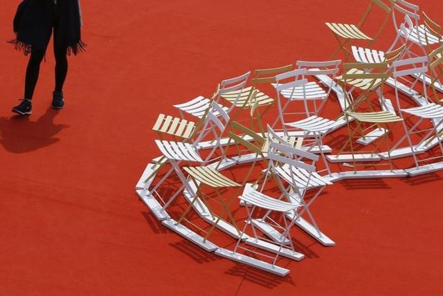A woman walks past chairs displayed on a red carpet in the Palace Festival on the eve of the opening ceremony. (REUTERS) A woman walks past chairs displayed on a red carpet in the Palace Festival on the eve of the opening ceremony. (REUTERS)