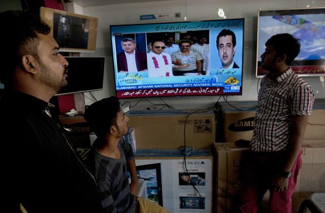People watch news about the release of Ali Haider Gilani at a shop in Karachi, Pakistan, Tuesday, May 10, 2016. (AP)