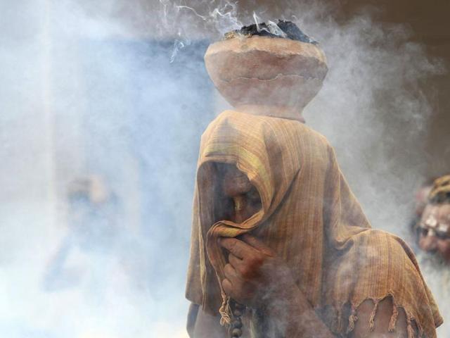 A Sadhu covers his face as an earthen pot with burning "Upale" (or dried cow dung cakes) rests on his head during a prayer ceremony at the Simhastha Kumbh Mela in Ujjain. (REUTERS) 