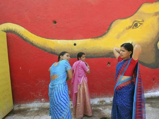 Women comb their hair in front of a mural after taking a holy dip in the Shipra river during Simhastha Kumbh Mela in Ujjain. (REUTERS) 