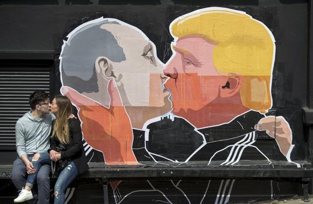 A couple kisses in front of a graffiti depicting Russian President Vladimir Putin, left, and Republican presidential candidate Donald Trump. (AP)