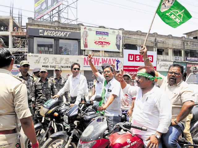 JMM workers enforcing the bandh in Ranchi, even as policemen look on.(Diwakar Prasad / Hindustan Times)