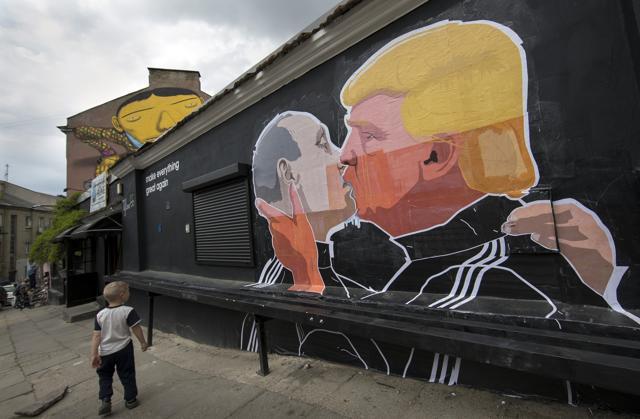 A child walks past a graffiti depicting Russian President Vladimir Putin, left, and Republican presidential candidate Donald Trump. (AP)