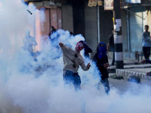 A masked protester throws back an exploded tear gas shell at Indian policemen during a protest in Srinagar on April 12.(AP) A masked protester throws back an exploded tear gas shell at Indian policemen during a protest in Srinagar on April 12.(AP)