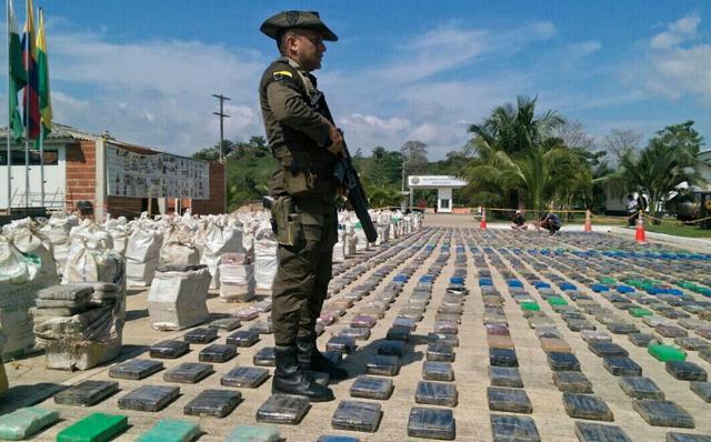 Handout picture released by the Colombian police showing a Colombian police officer standing guard over eight tons of seized cocaine in Turbo, Antioquia department, on May 15, 2016. (AFP)