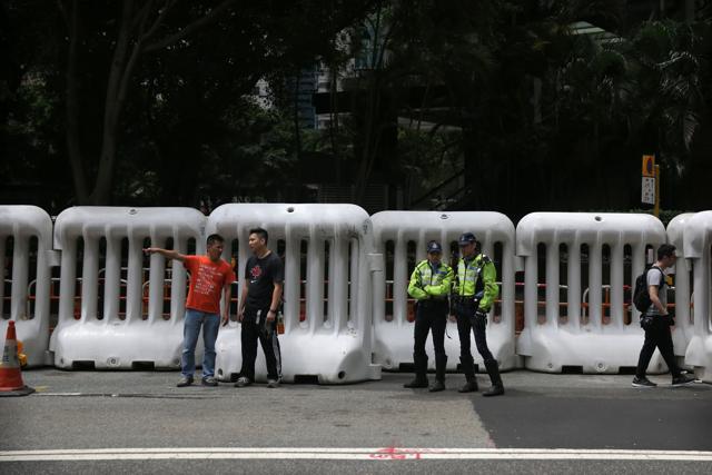Police officers (C) stand in front of large barricades erected along a road in Hong Kong as authorities prepare for possible protests. (AFP Photo) Police officers (C) stand in front of large barricades erected along a road in Hong Kong as authorities prepare for possible protests. (AFP Photo)
