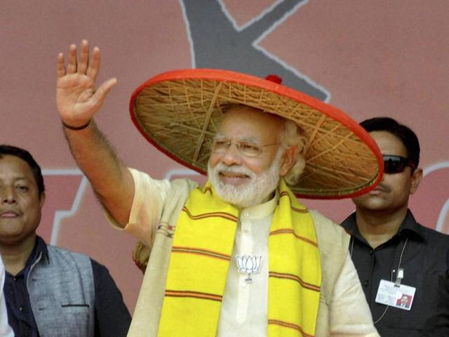 Prime Minister Narendra Modi, wearing an Assamese traditional hat, waves to the crowd during an election rally in Majuli, Assam. (PTI Photo)